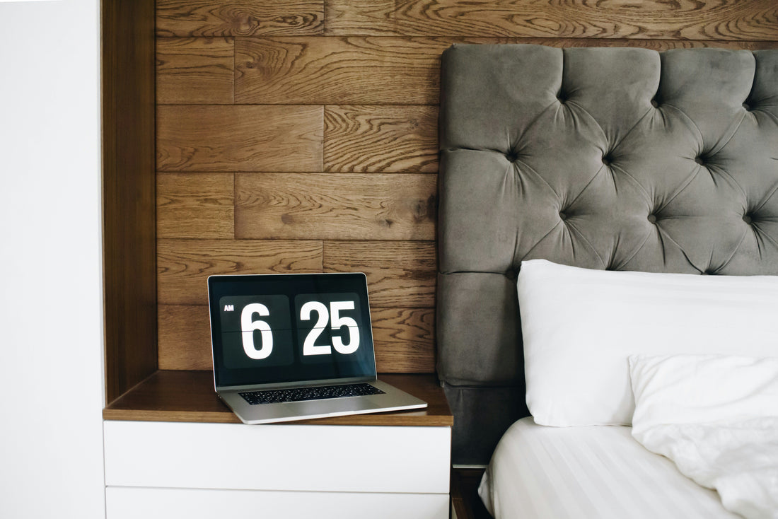Open laptop with time displayed next to bed